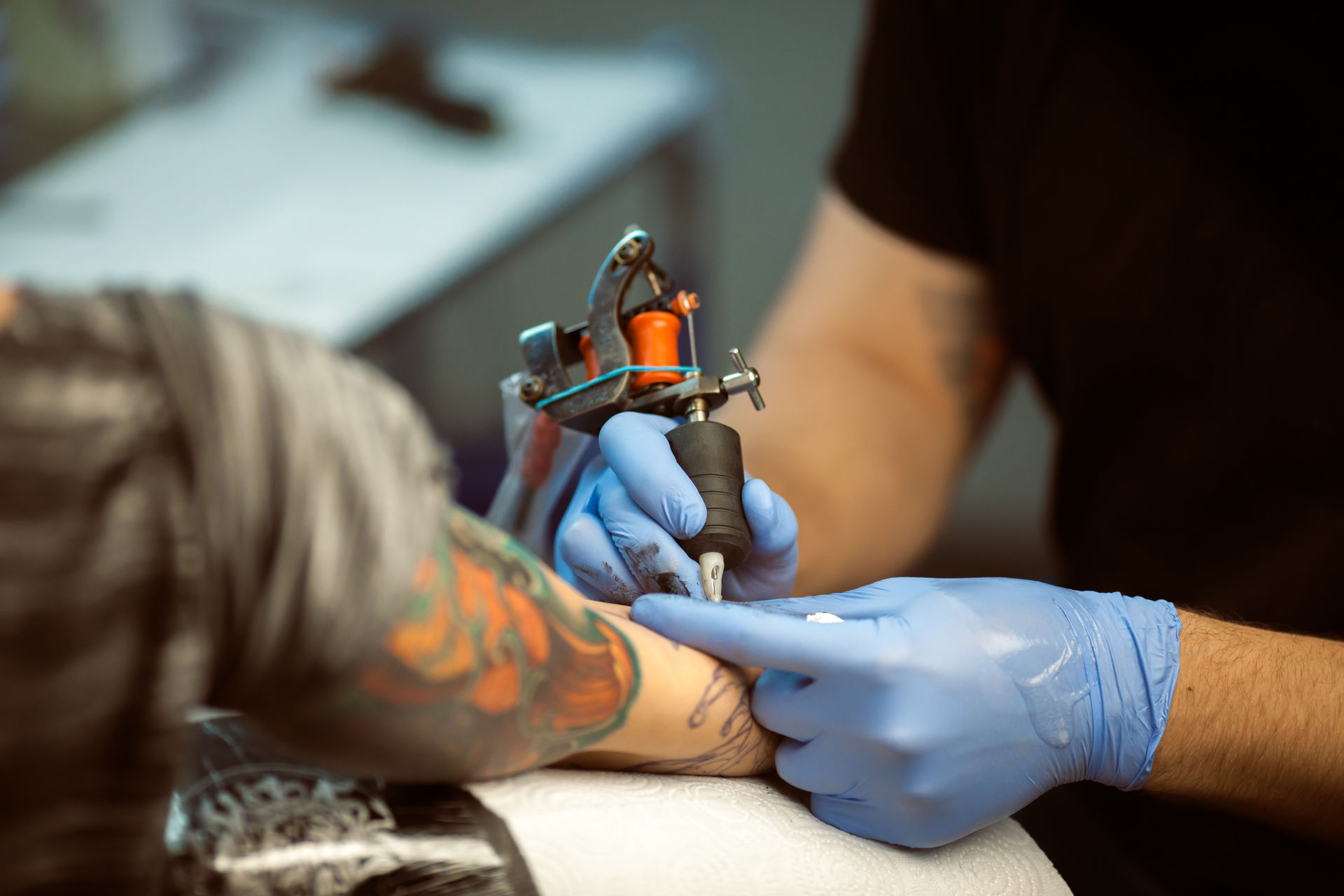 Arm being tattooed by tattoo artist with gloves on